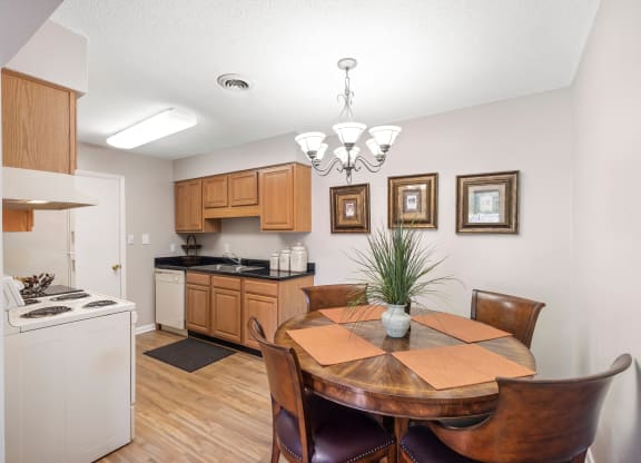 a dining area with a table and chairs and a kitchen in the background