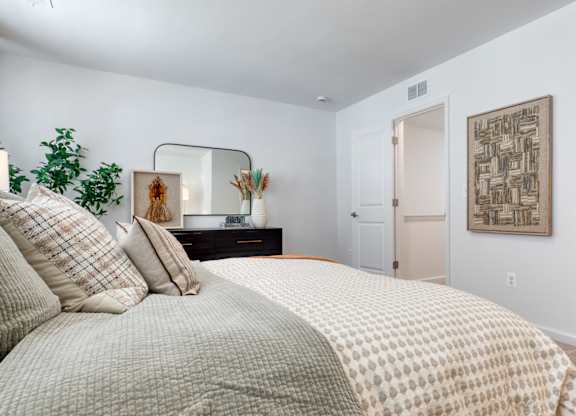 A bedroom with a large bed and a mirror on the wall at The Mark Townhomes Apartments, Harrisonburg