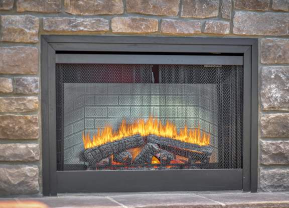 A fireplace with a stone wall behind it.