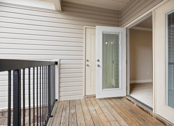 the deck of a home with a door open to a balcony