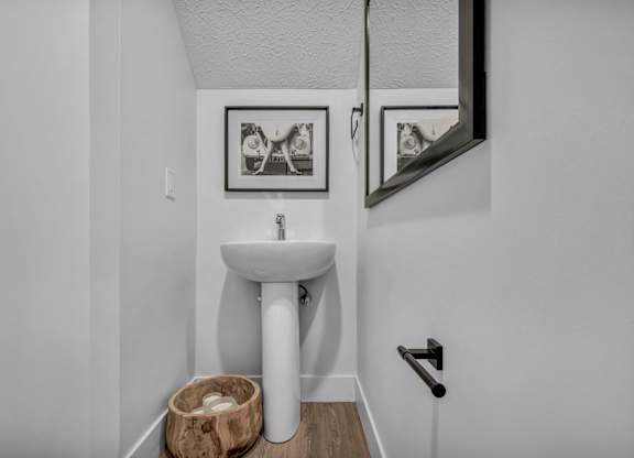 A bathroom with a white pedestal sink and a mirror above it.