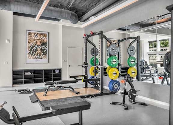 A gym with a variety of equipment including weights and a bench.