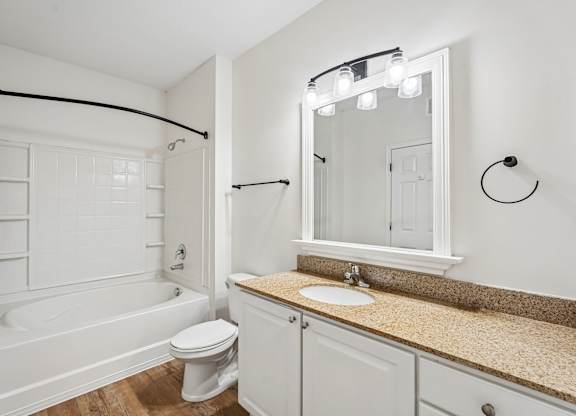 A white bathroom with a tub, toilet, sink and mirror.