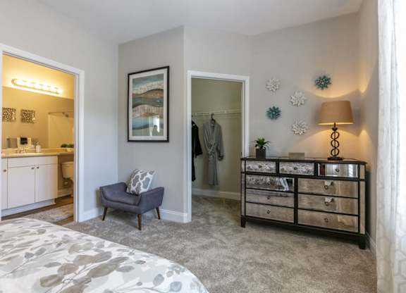 A bedroom with a grey carpet and a grey bed.
