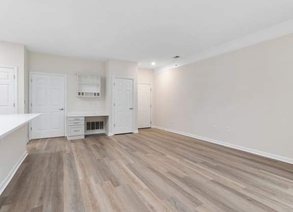 an empty living room and kitchen with white walls and wood flooring  at The Charleston, Columbus