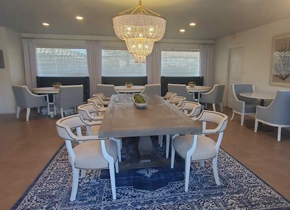 A dining room with a large table and chairs.