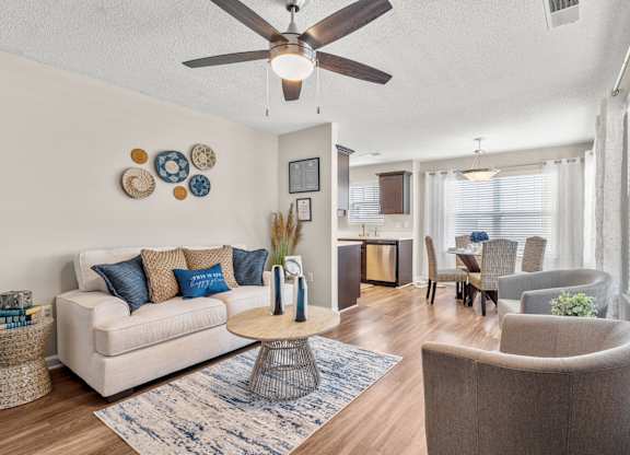 A living room with a white couch, a coffee table, and a ceiling fan.