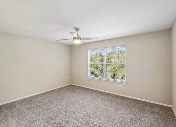 A room with a ceiling fan and a window with blinds.