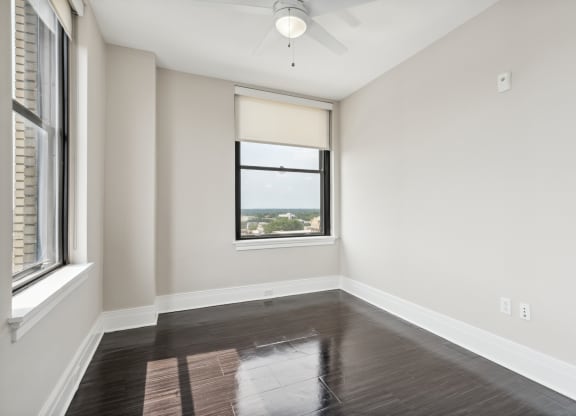 an empty bedroom with a window and a ceiling fan