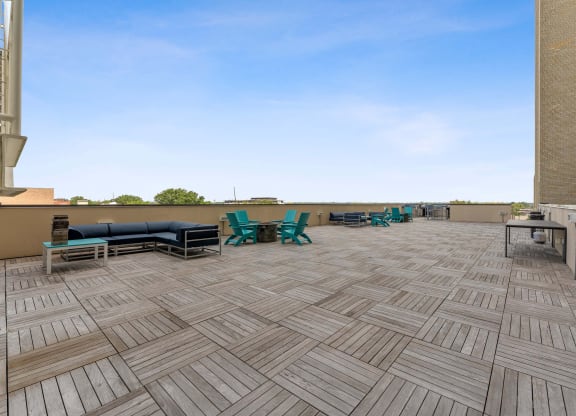 a patio with a grill and lounge chairs on top of a building