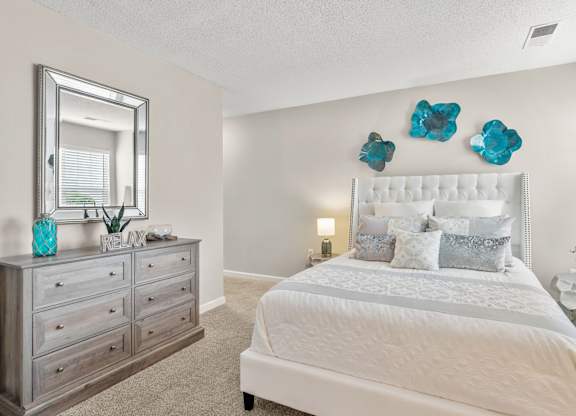 A bedroom with a large bed, a dresser, and a mirror.