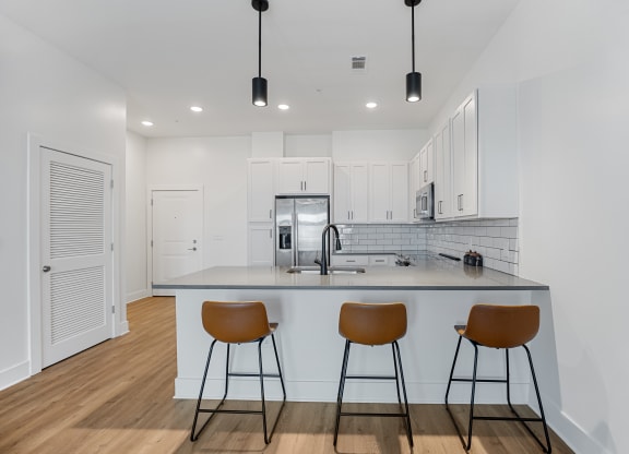 a kitchen with a large island with three stoolsat Oak Grove at Blake Farm, Wilmington, North Carolina