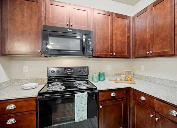 A black stove and microwave in a kitchen with brown cabinets.