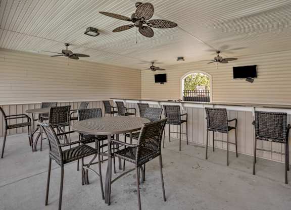 A patio with a table and chairs and a ceiling fan.