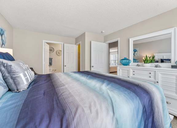 A bedroom with a bed covered in a blue and grey striped comforter.