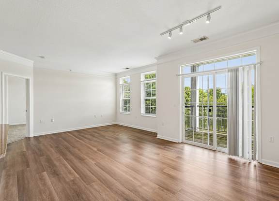 A room with wooden floors and a sliding glass door leading to a backyard.
