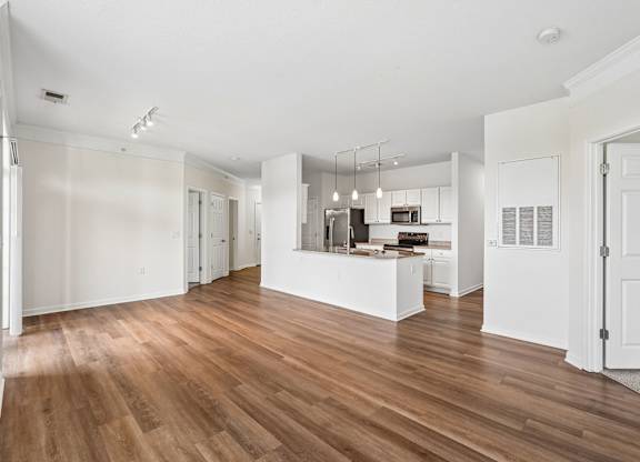 A spacious room with wooden flooring and white walls.