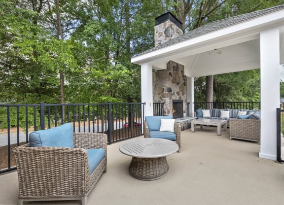 a covered patio with wicker furniture and a fireplace