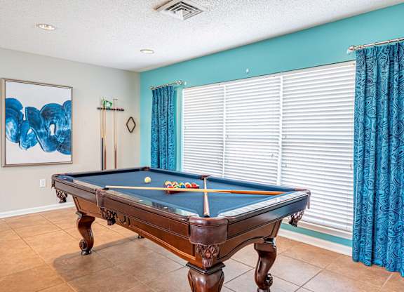 A pool table in a room with a blue wall.