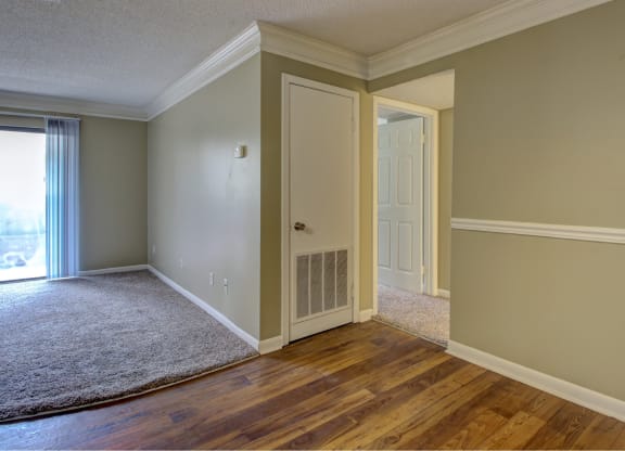 an empty living room with wood floors and a door to a closet