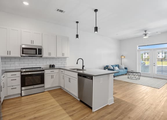 a kitchen with white cabinets and stainless steel appliancesat Oak Grove at Blake Farm, Wilmington, 28411