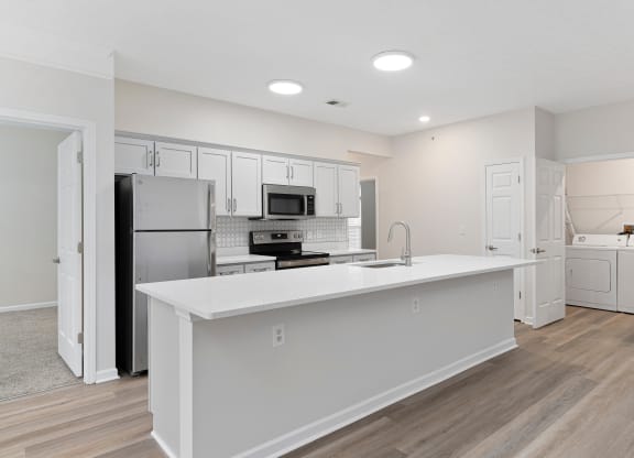 a white kitchen with a large island and stainless steel appliances at The Charleston, Columbus, OH