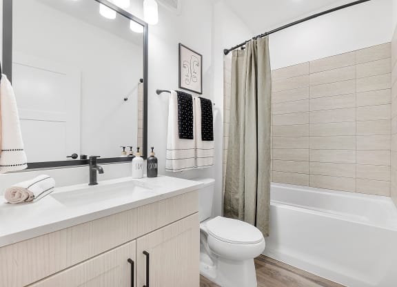 a bathroom with a white sink and toilet next to a white bathtub with a shower curtain