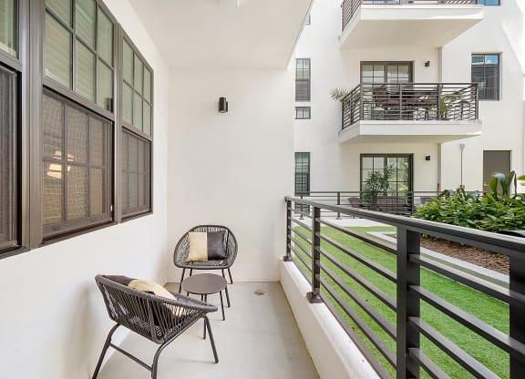 a balcony with two chairs and a grassy area