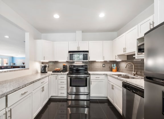 a kitchen with white cabinets and black appliances