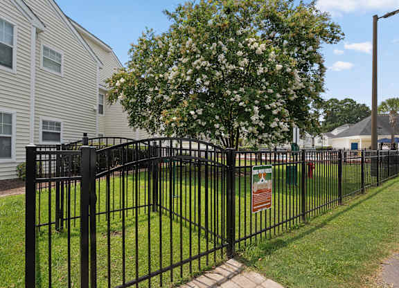 A black metal fence surrounds a green lawn.