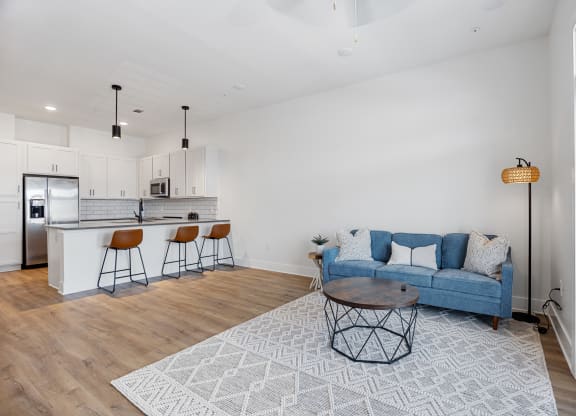 a living room with a blue couch and a kitchen with a barat Oak Grove at Blake Farm, Wilmington, NC, 28411