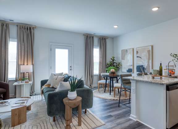 A modern kitchen with a green couch and a dining table at The Mark Townhomes Apartments, Harrisonburg, VA