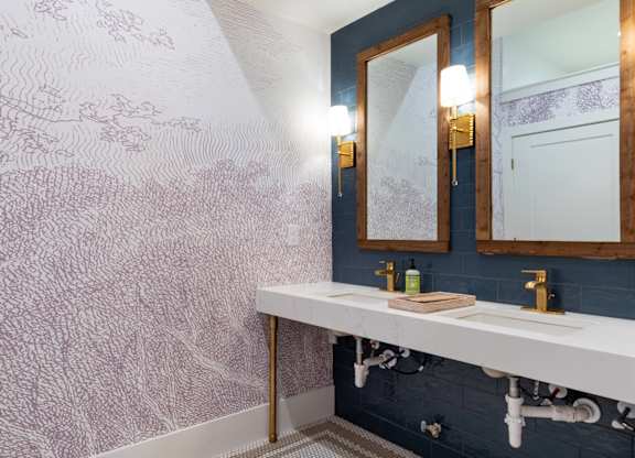 A bathroom with a white sink and a wallpapered wall.