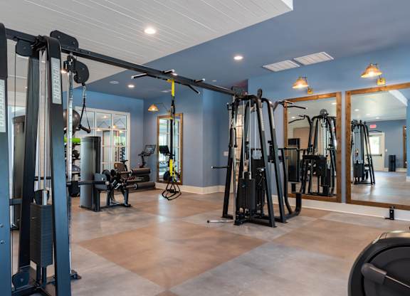 A gym with a variety of equipment including treadmills, weights, and exercise machines.