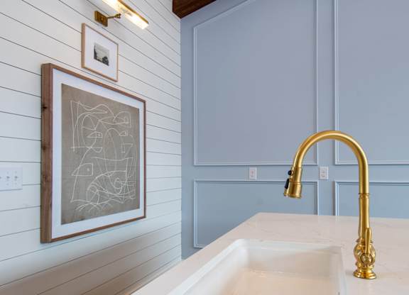 A bathroom with a sink and a framed drawing on the wall.