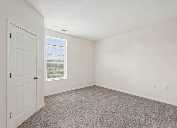 A room with a carpeted floor and a window showing a view of a street.