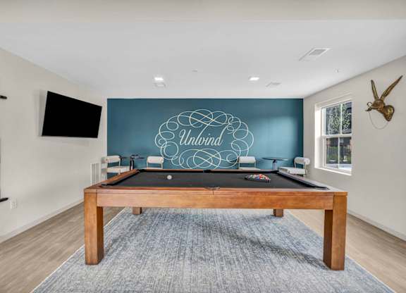 A pool table with a blue cloth and a wooden frame is in the middle of the room.