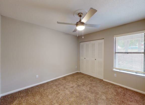 a bedroom with a ceiling fan and window