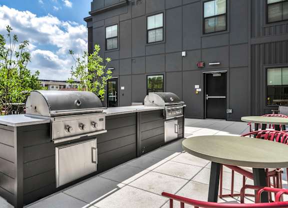 A barbecue grill is situated on a patio outside a building.