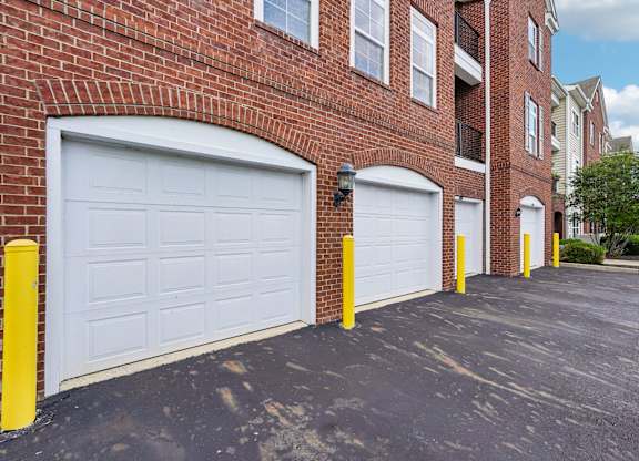 A row of garage doors in front of a brick building.