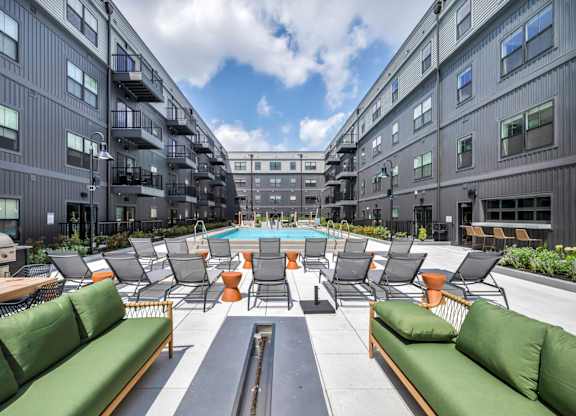 A large outdoor seating area with green couches and tables.