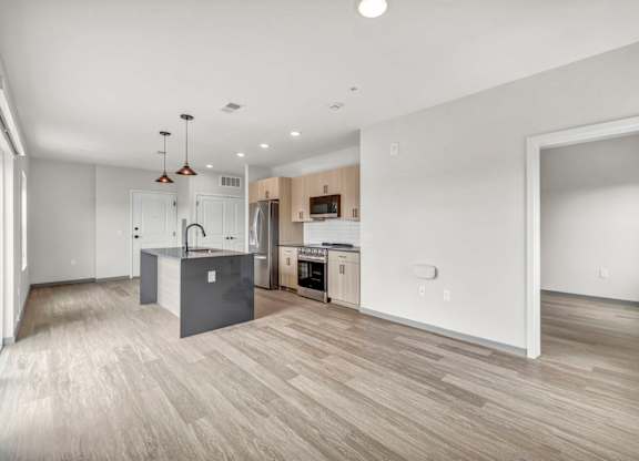 A spacious kitchen and living room with wooden flooring and modern appliances.