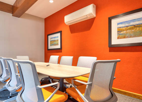 A conference room with a table, chairs, and two framed pictures on the wall.