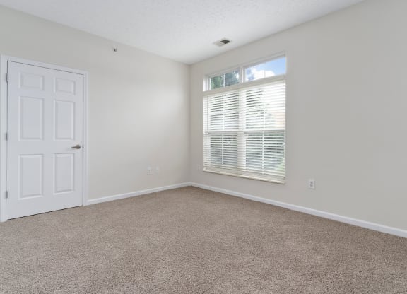 an empty bedroom with a window and a white door at The Charleston, Columbus