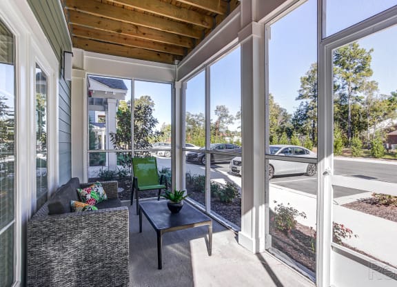 a covered porch with a couch and a coffee table and large windows at Barclay Place Apartments, Wilmington