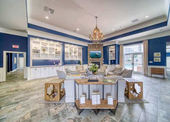 A large, open-concept living space with a stone floor and a chandelier hanging from the ceiling.
