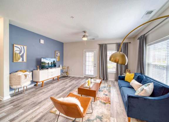 A living room with a blue couch and a wooden floor.