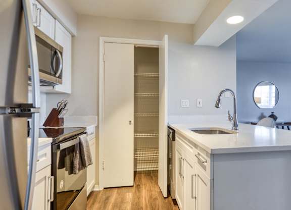 A modern kitchen with white cabinets and a stainless steel refrigerator.