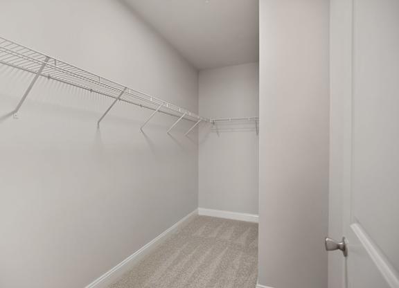 A white hallway with a carpeted floor and a door on the right.