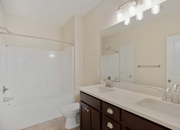 A white bathroom with a toilet, sink, and shower.